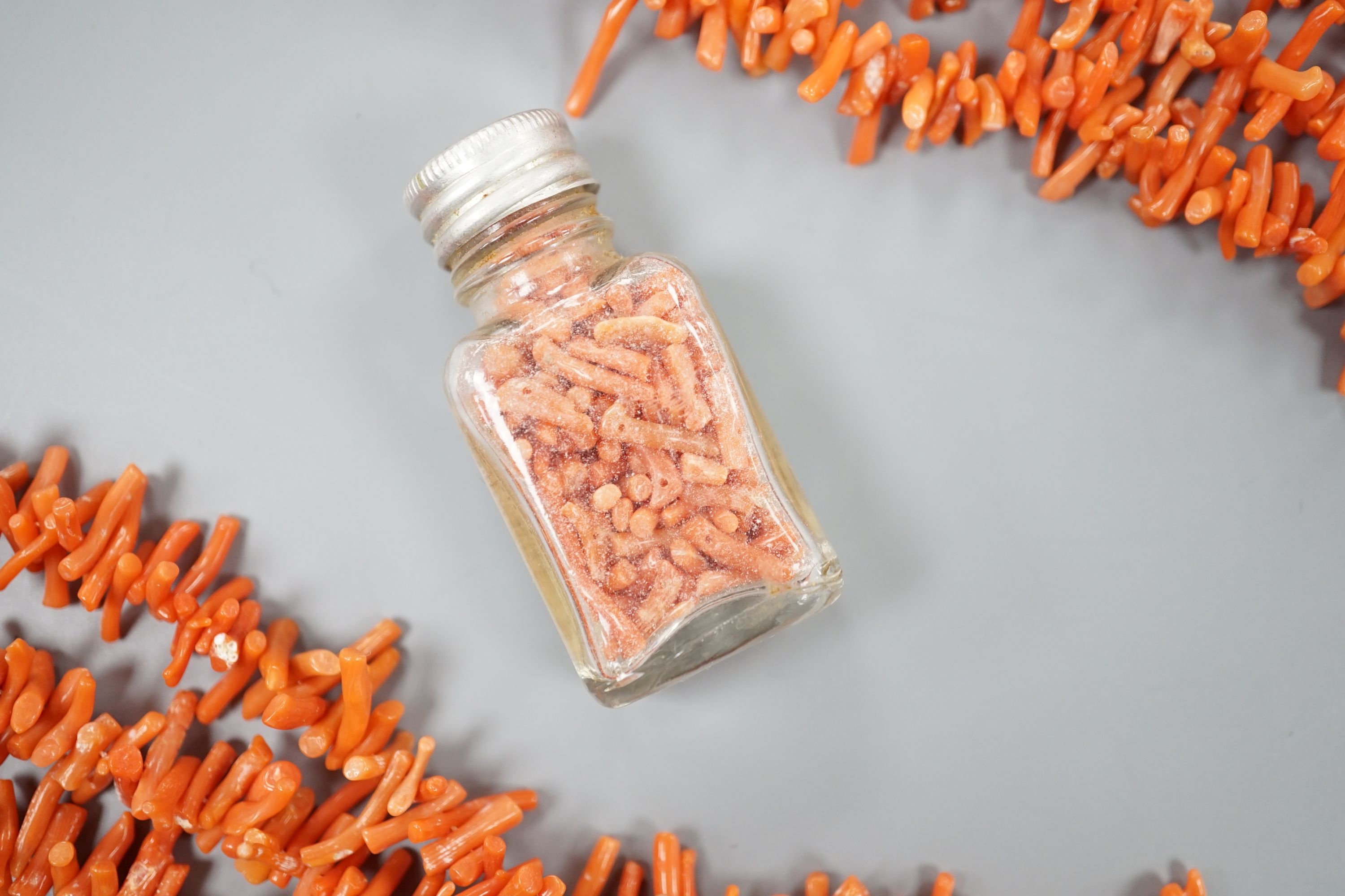 A triple strand branch coral necklace, 86cm, gross weight 141 grams and a small jar of loose branch coral.